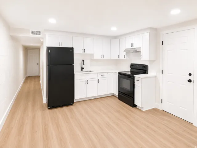 Compact kitchen featuring white cabinetry, light-toned wood-finish flooring, a black appliance suite, white countertops, and recessed lighting