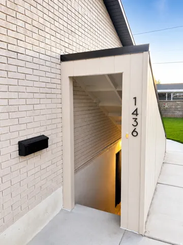 Exterior entrance featuring light-colored brick siding and a black mailbox