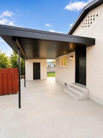 Expansive concrete carport featuring a black slatted ceiling and supporting columns