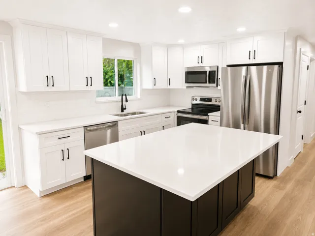 Modern kitchen featuring a central island with a white countertop and dark cabinetry