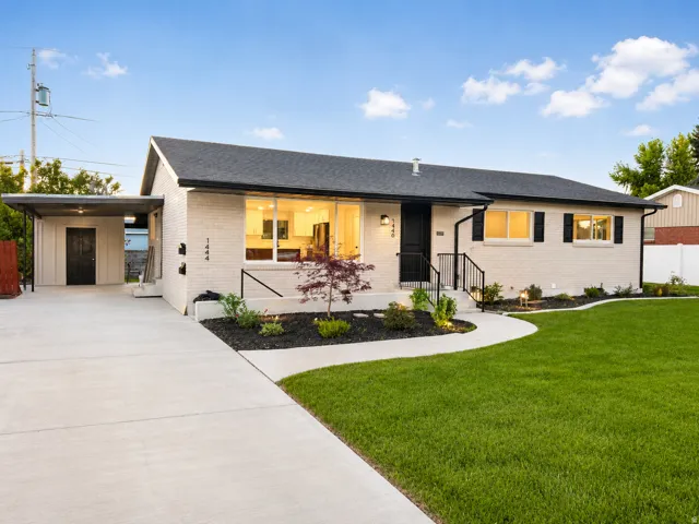Contemporary single-story residence with a light brick exterior, dark asphalt shingle roof, and black window shutters