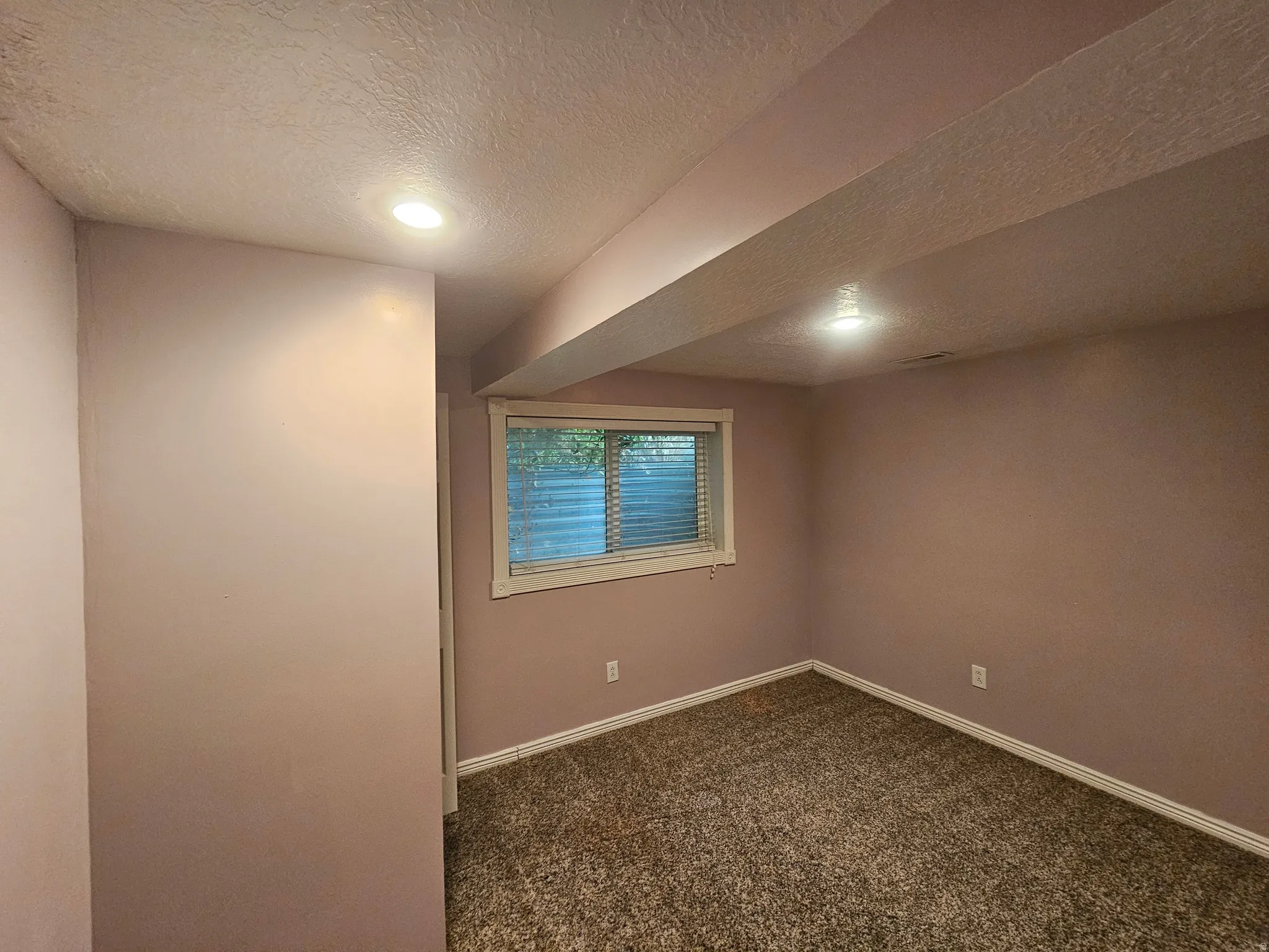 Carpeted room with recessed lighting, base molding, textured ceiling, and a window with blinds