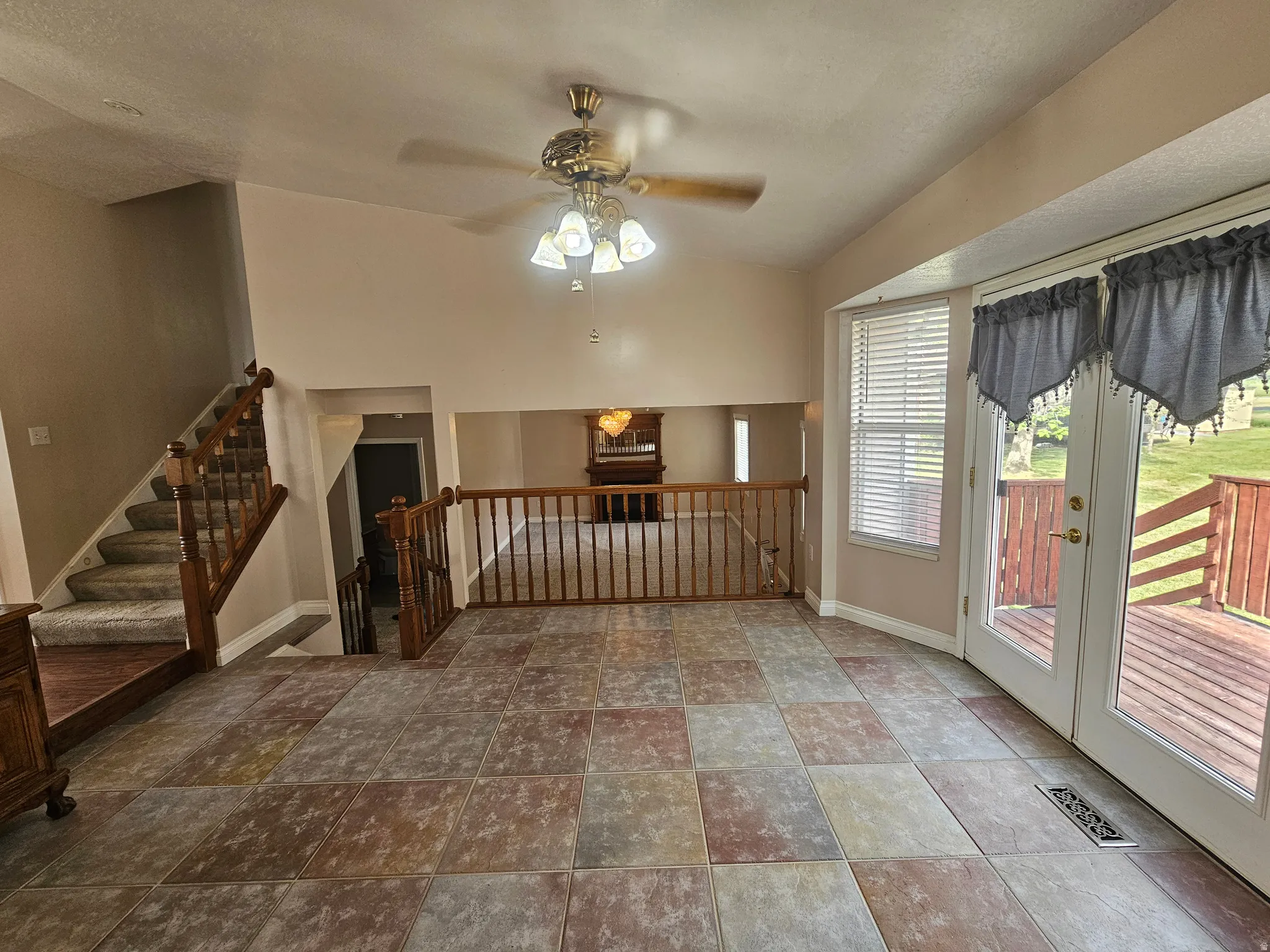 Open-concept living area featuring multi-tone tile flooring and a double-door exterior exit to a wood deck