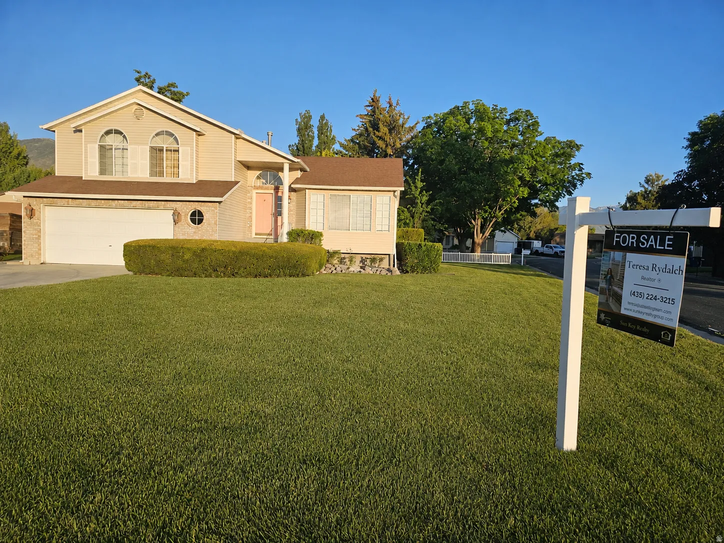 Two-story residence featuring a two-car garage, light-colored siding, and a brick facade