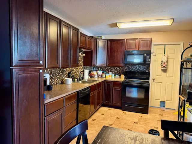 Kitchen featuring dark wood-finish cabinetry, mosaic tile backsplash, and stone-look countertops