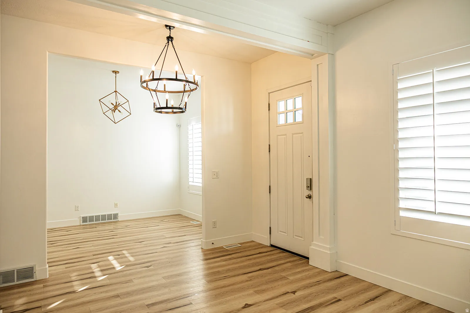 Entryway featuring wood-finish flooring, a white paneled front door with glass inserts, and a contemporary chandelier