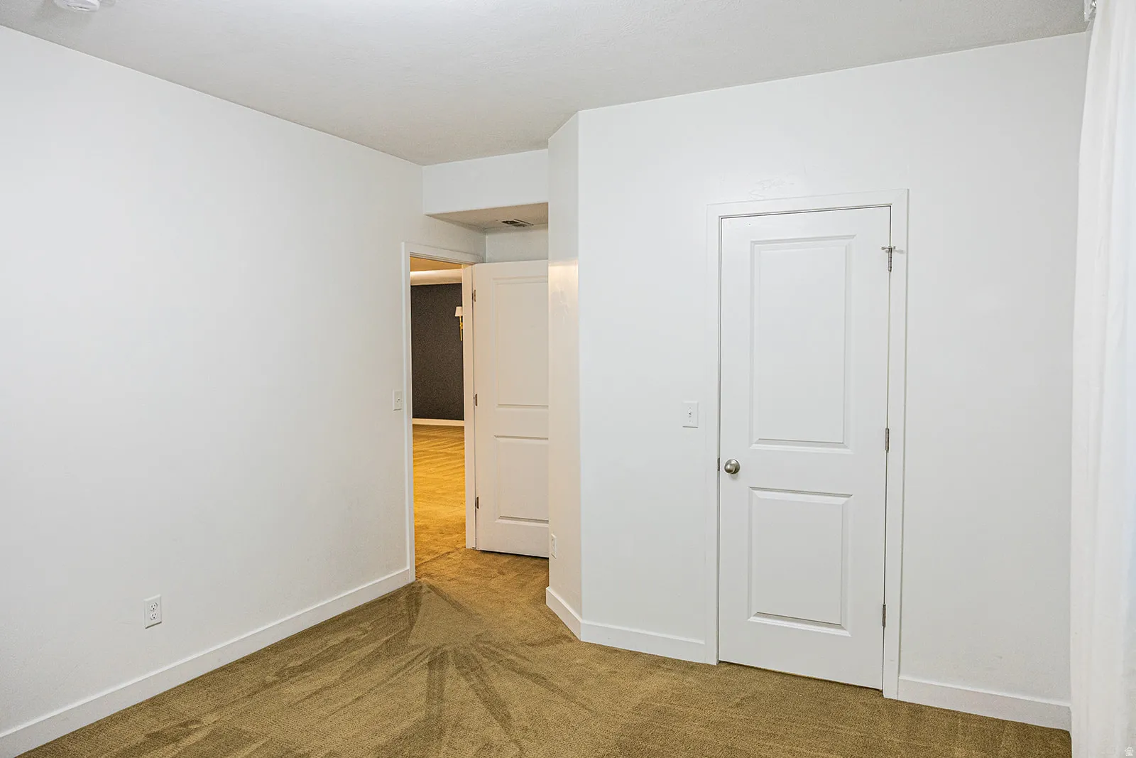 White walls and baseboards with neutral carpet flooring