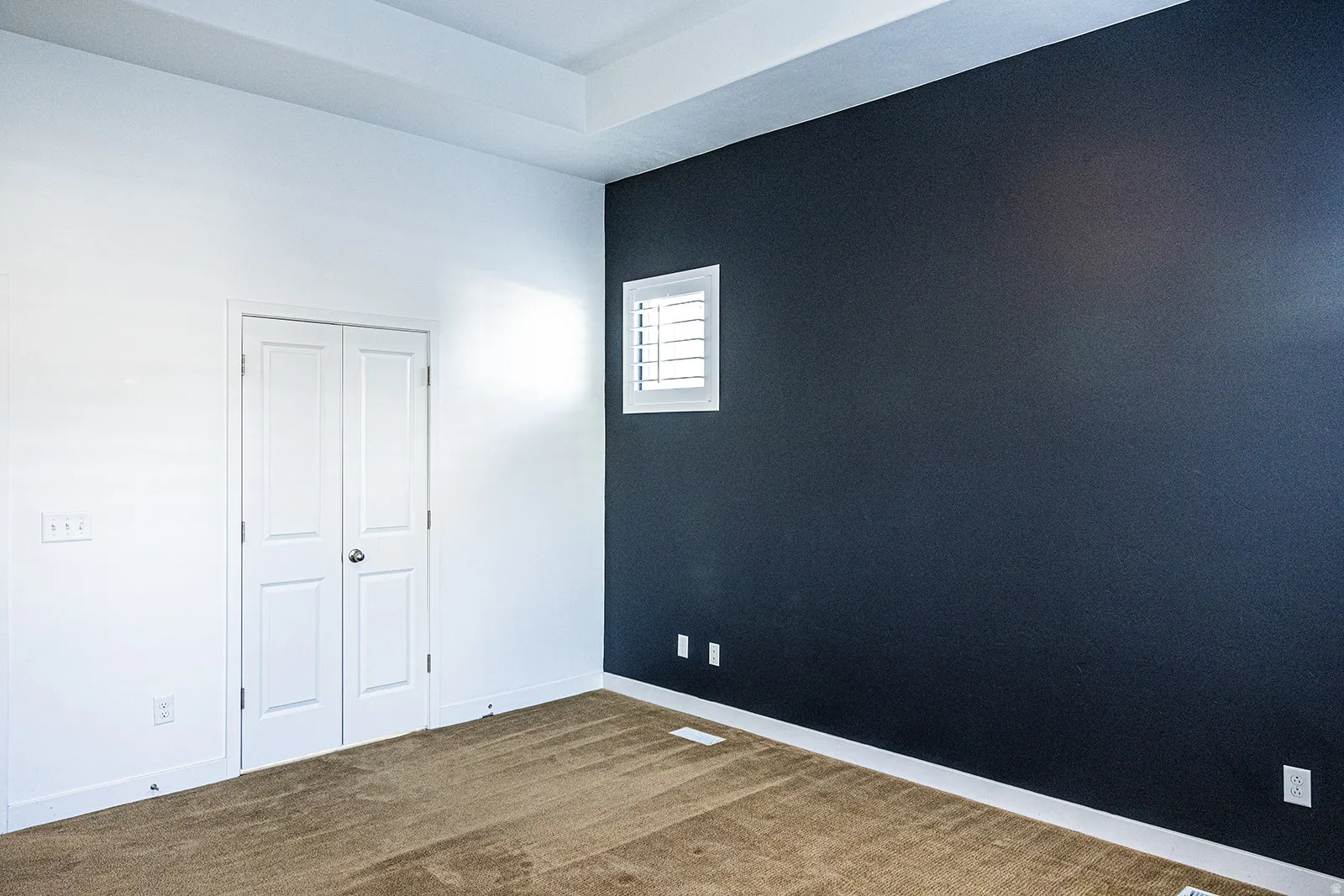 Carpeted room featuring a dark accent wall and white trim