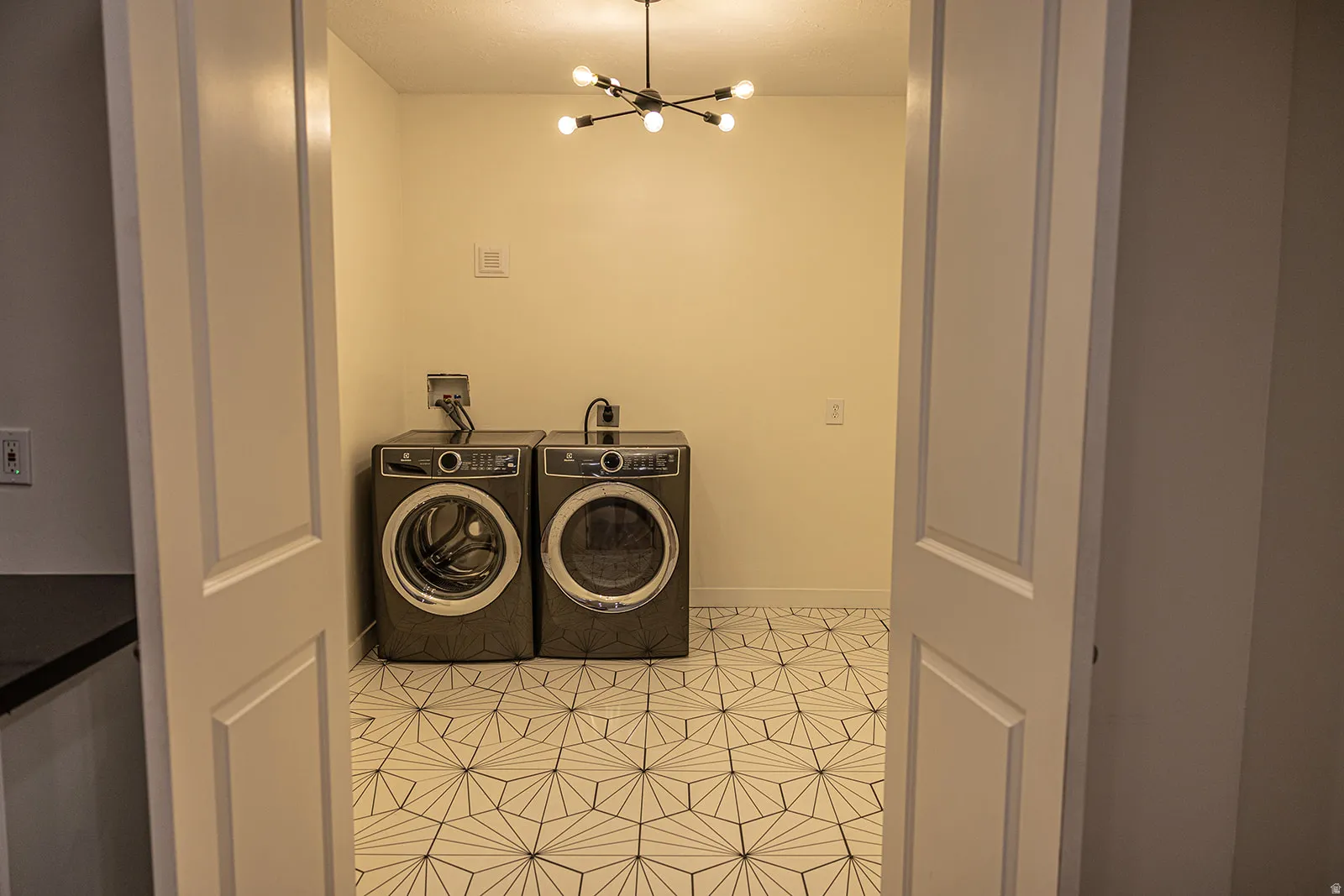 Dedicated laundry space featuring a contemporary geometric tile floor pattern