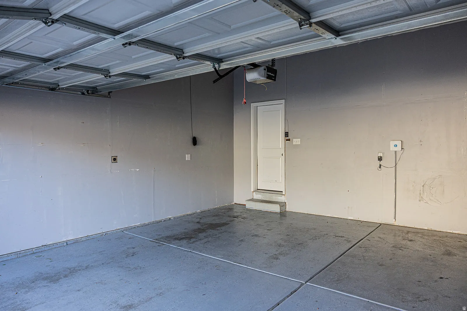 Two-car garage featuring a gray concrete floor, light gray walls, and a white overhead garage door