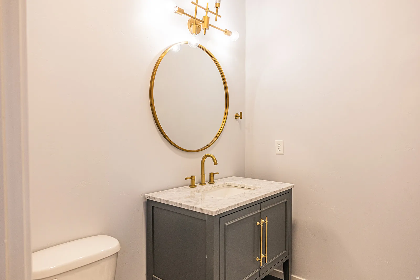 Gray vanity with gold hardware, a white countertop, and an integrated sink
