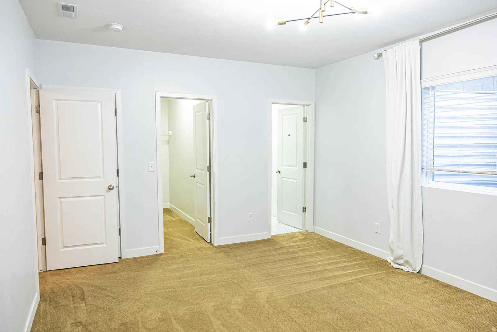 Carpeted room featuring light-colored walls, white trim, and a modern ceiling light fixture