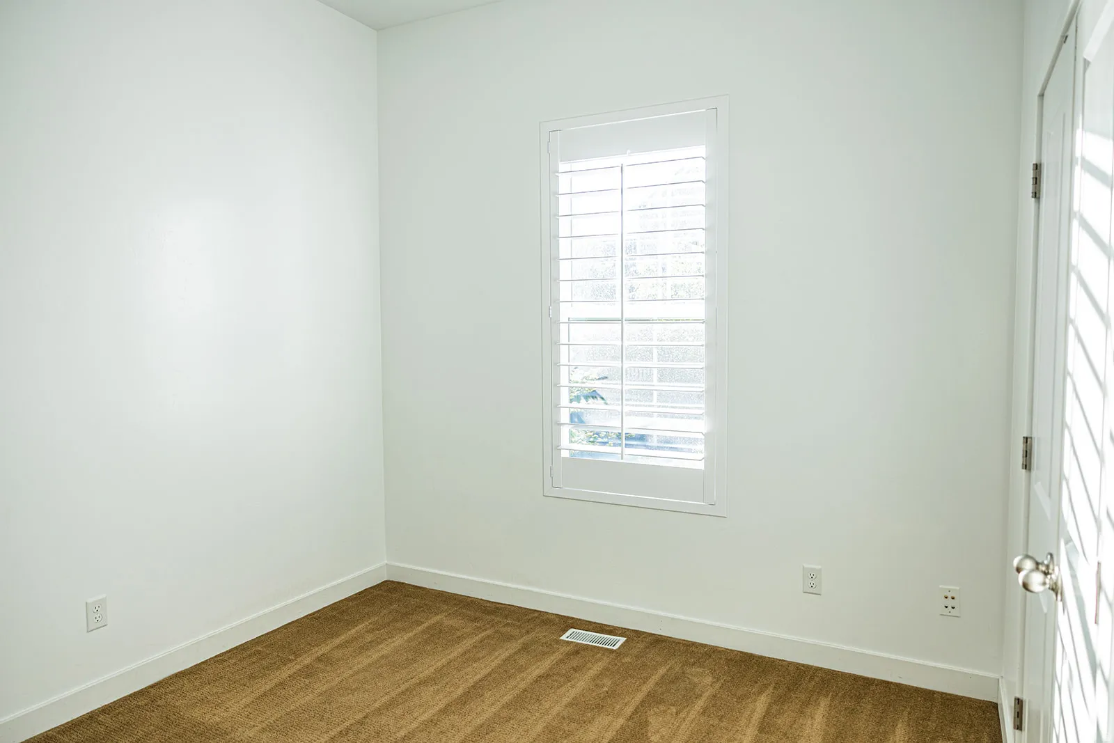 Room featuring white walls, brown carpet flooring, and white baseboards