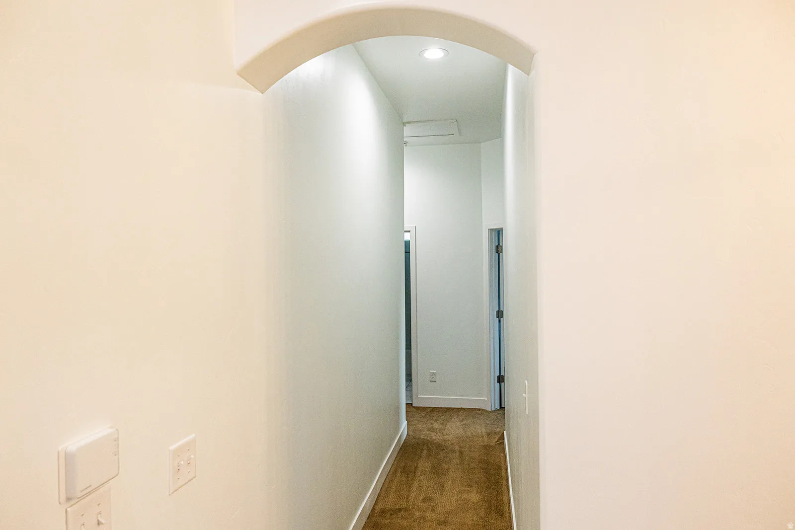 Archway entry to a hallway featuring recessed lighting and wood-finish flooring