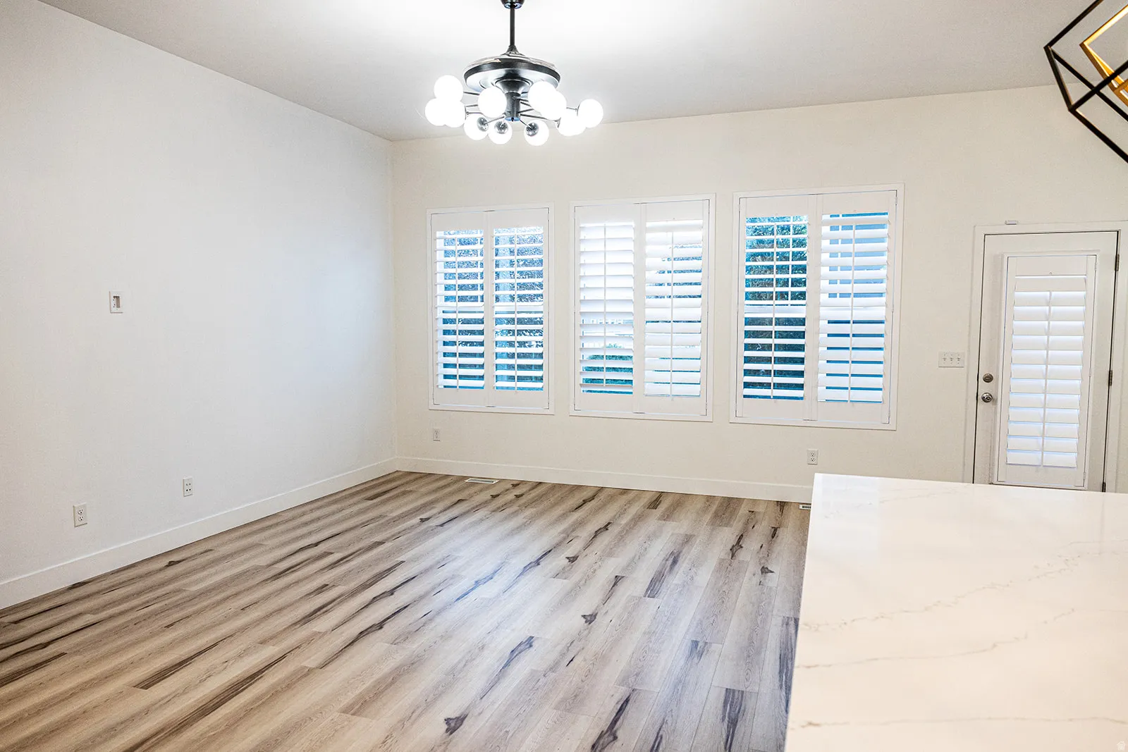 Bright interior space featuring wood-finish flooring and a contemporary multi-bulb chandelier