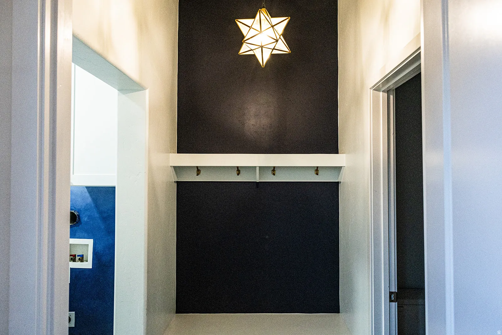 Entryway featuring a decorative star pendant light, a built-in shelf with integrated hooks, and a dark accent wall