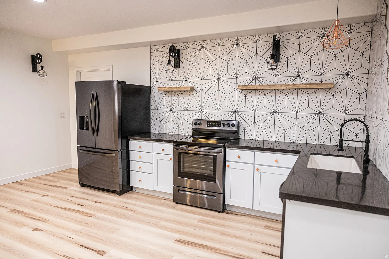 Modern kitchen featuring a geometric tile backsplash, dark stainless steel appliances, white cabinetry with wood-finish knobs, dark countertops, and wood-finish flooring
