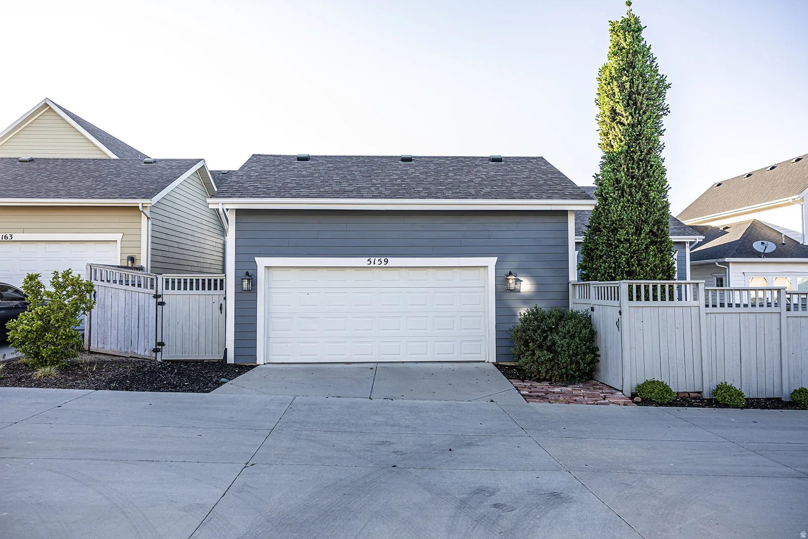 Exterior showcasing blue horizontal siding, a white garage door, and a dark shingle roof