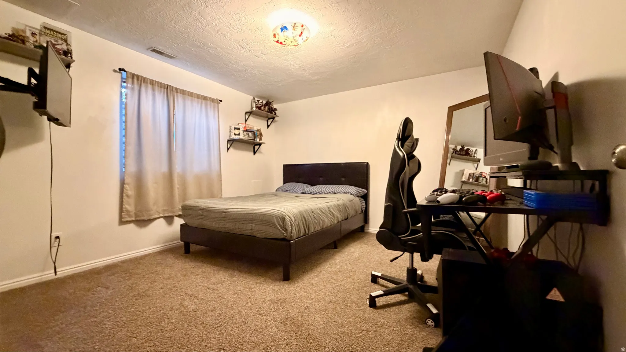 Carpeted room featuring a window with drapes, a built-in wall shelf, and a ceiling-mounted light fixture