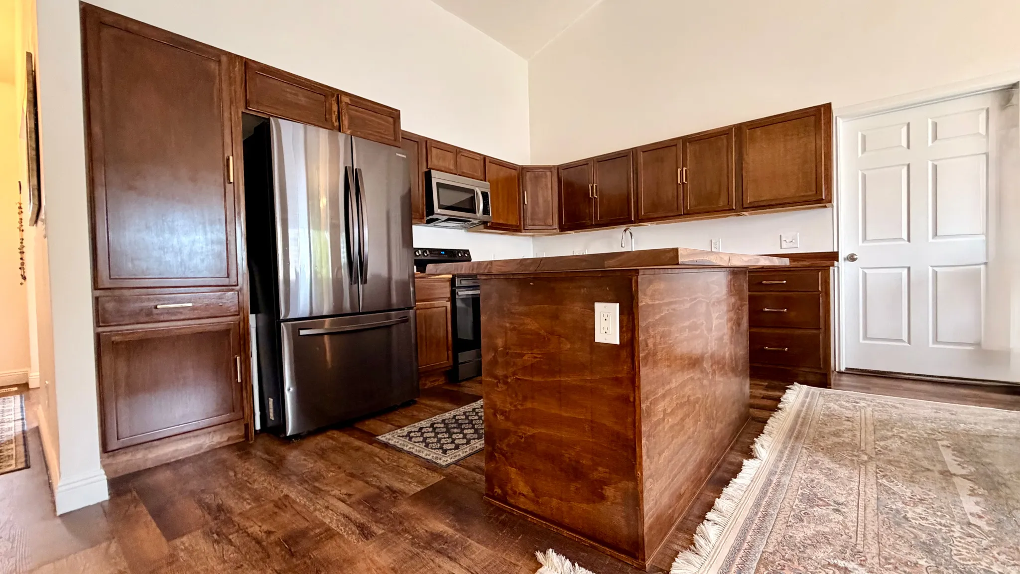 Kitchen featuring wood-finish flooring, dark wood cabinetry, a central island, and stainless steel appliances