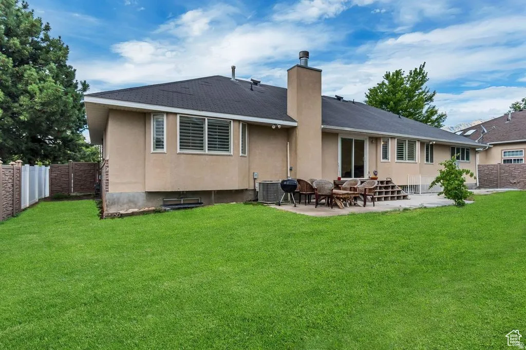 Spacious backyard featuring a large concrete patio, expansive lawn, and stucco exterior