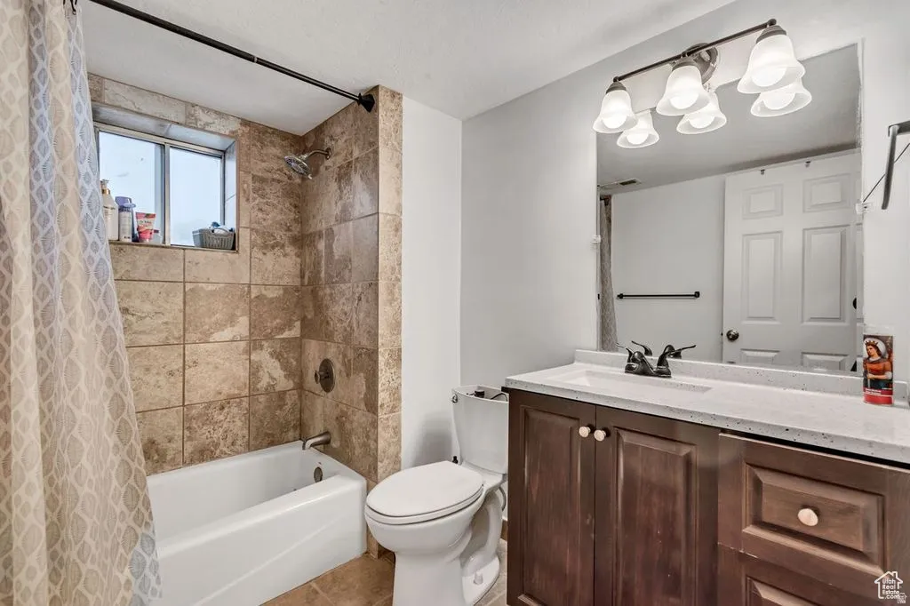 Bathroom featuring a tub/shower combination with natural stone-look tile surround and a window
