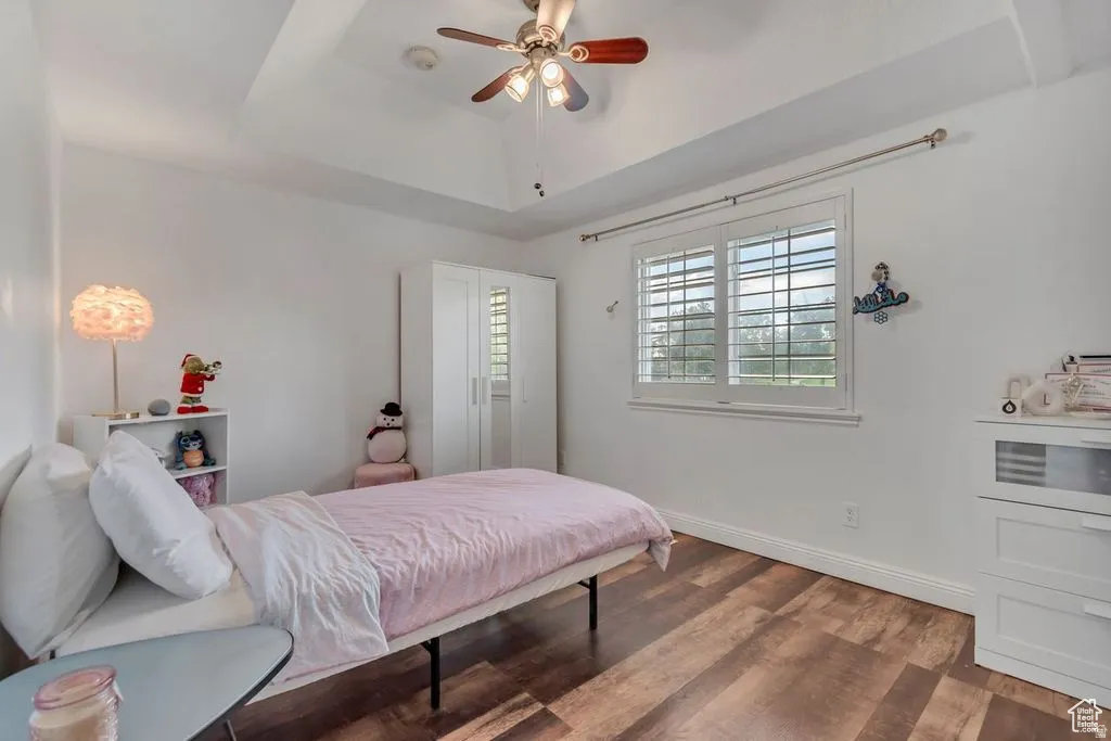 Bright interior space featuring wood-finish flooring, a tray ceiling, and a ceiling fan with integrated lighting