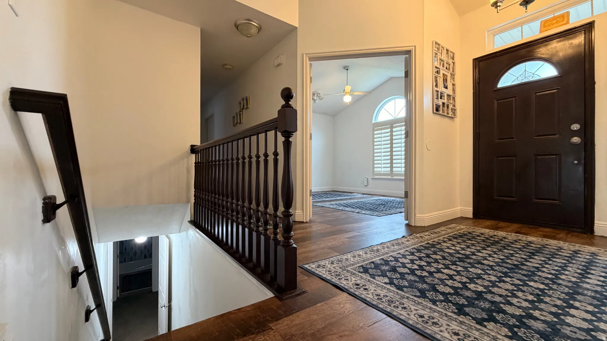 Entryway featuring a dark wood-finish door with an arched glass insert, complementing dark wood-finish flooring, and a decorative chandelier