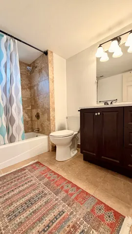 Bathroom featuring a built-in tub with tile surround, a dark wood-finish vanity with a light-toned countertop, and tile flooring