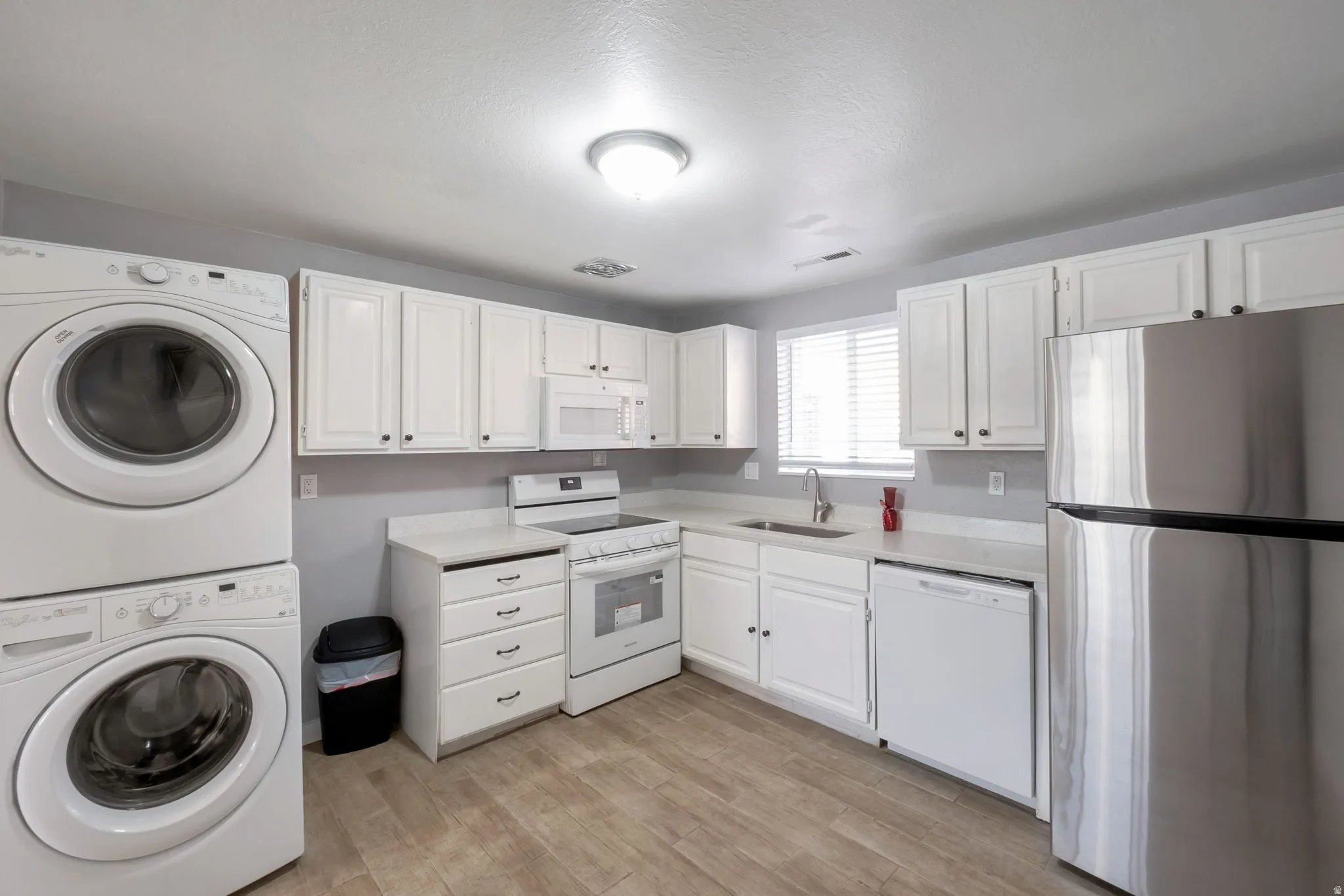 Kitchen area featuring white cabinetry, light-toned countertops, and wood-finish flooring
