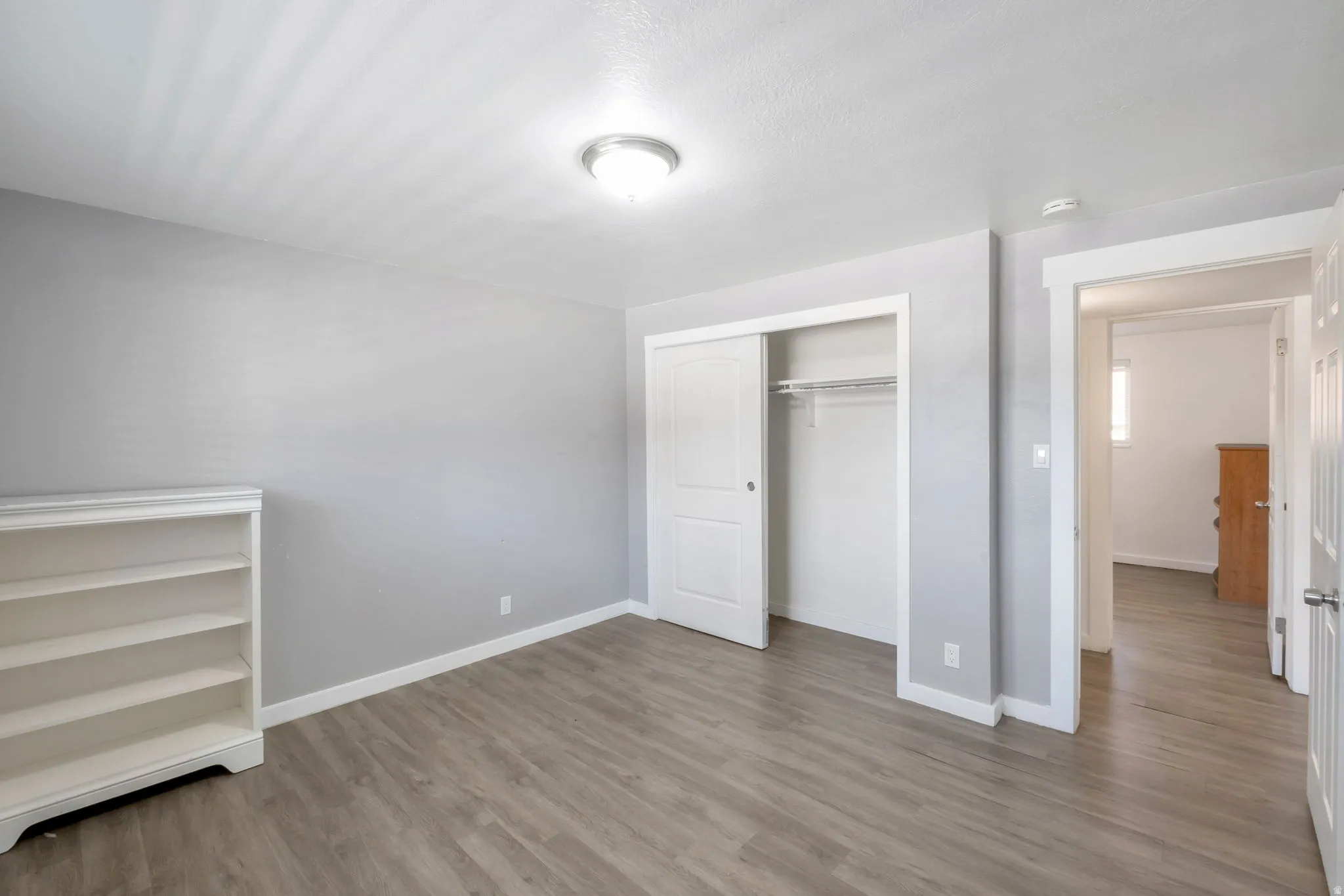 Interior room featuring wood-finish flooring and a built-in closet with sliding doors