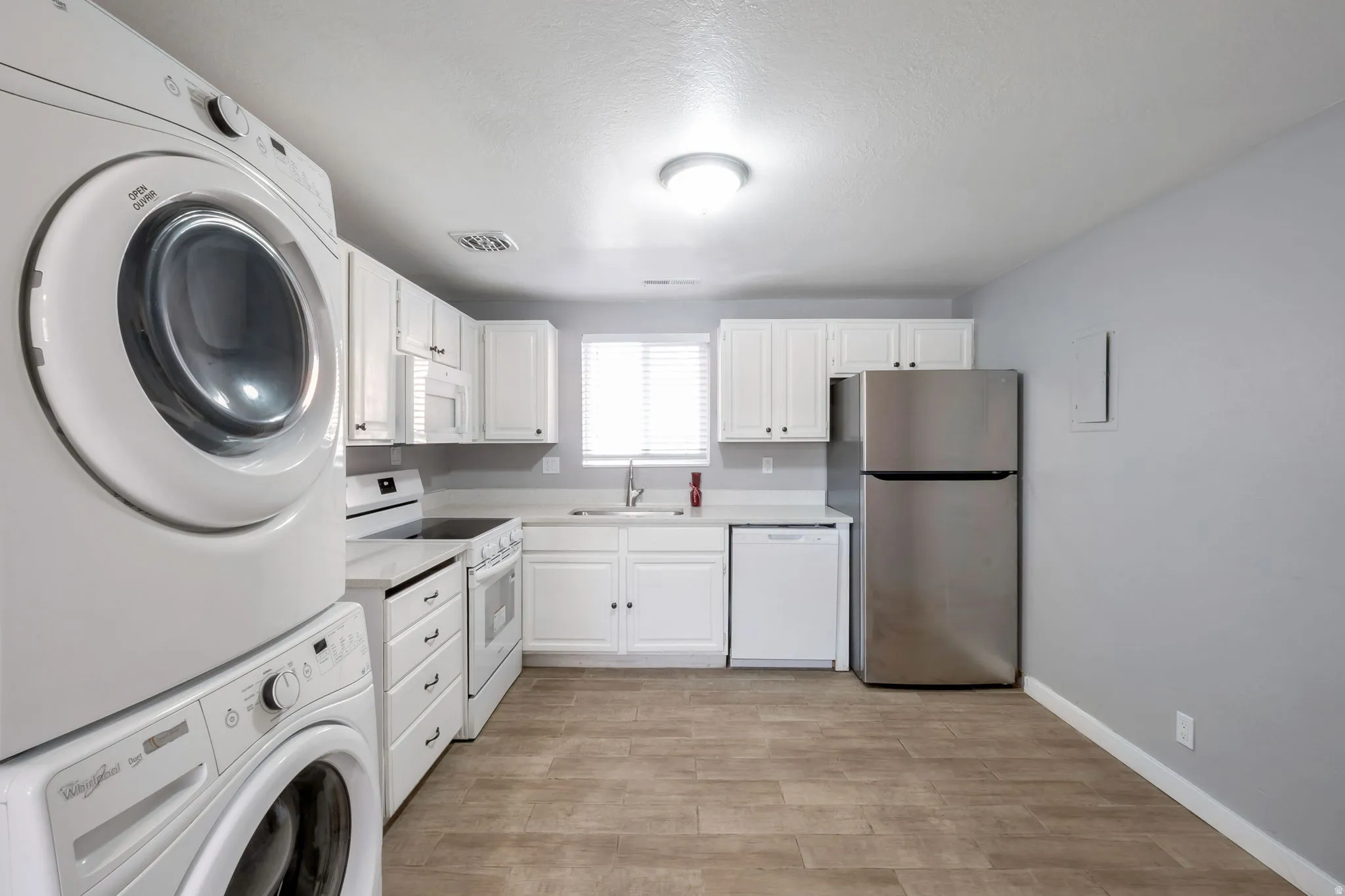 White kitchen cabinetry with integrated white appliances and stainless steel refrigerator