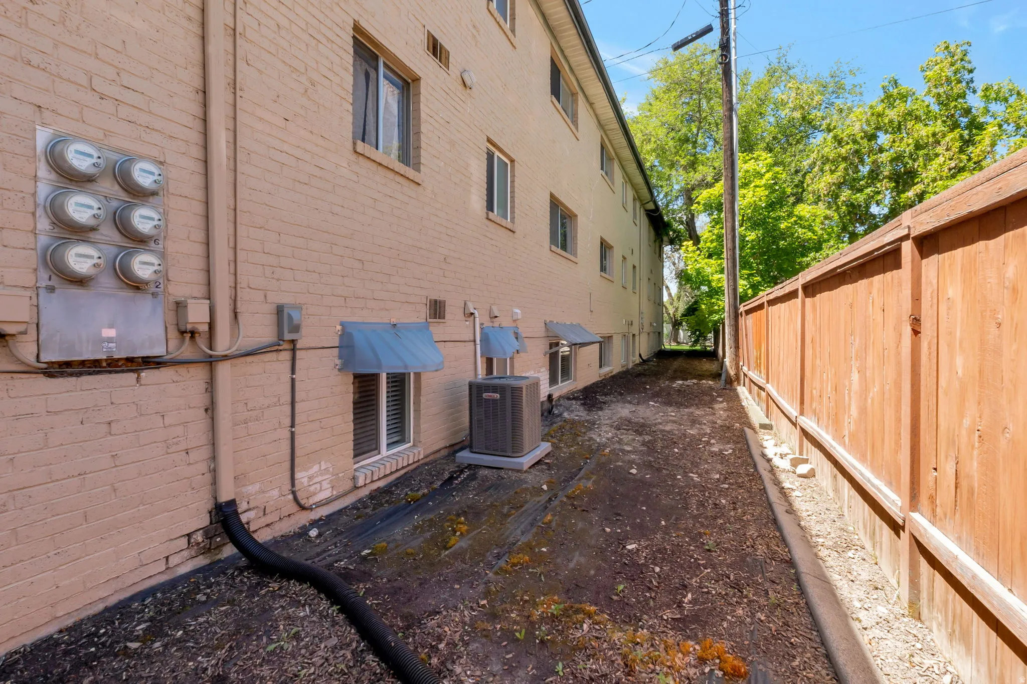 Brick exterior featuring multiple utility meters and window awnings