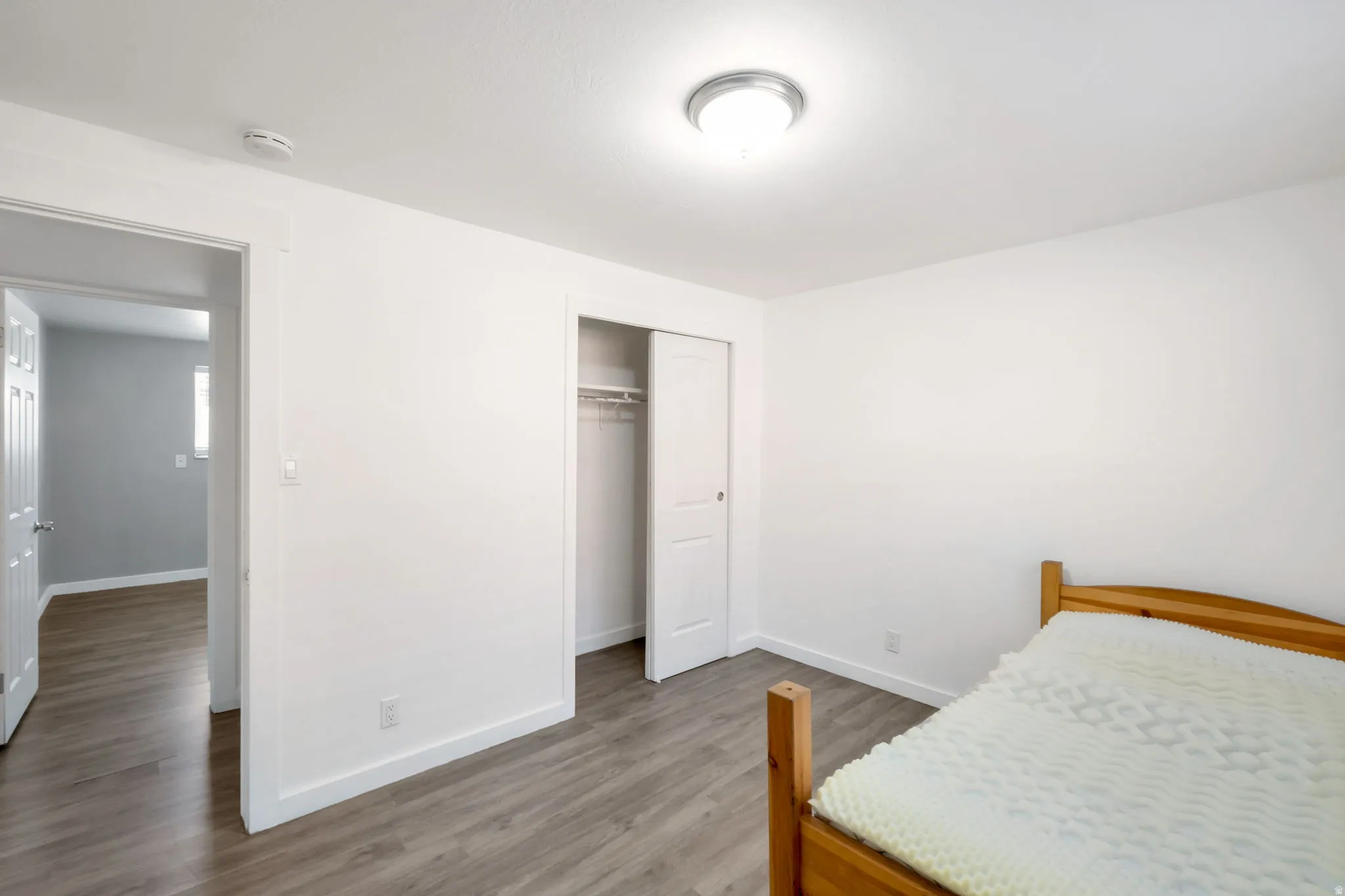 Bright room featuring wood-finish flooring, a flush-mount ceiling light fixture, and a spacious closet with sliding doors