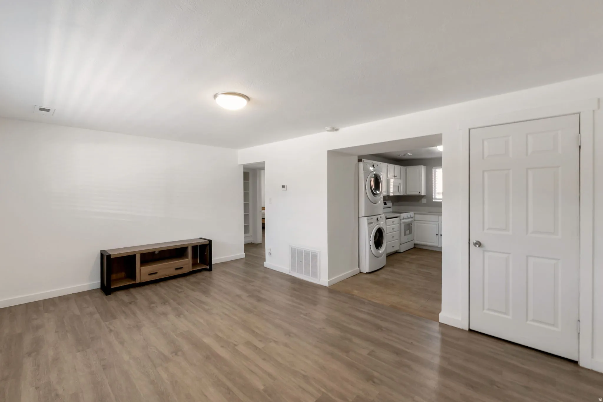 Open-concept living space featuring wood-finish flooring, white baseboards, and a neutral color palette