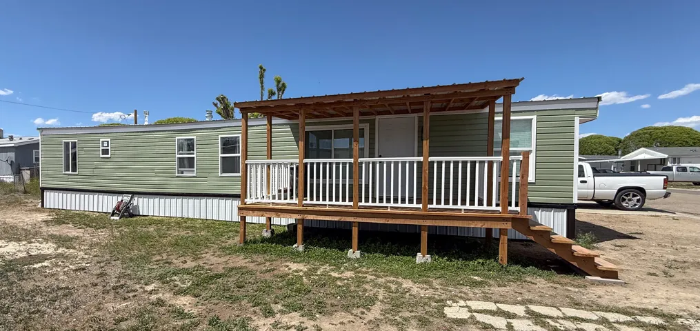 Property exterior featuring green horizontal siding, white trim, and multiple windows