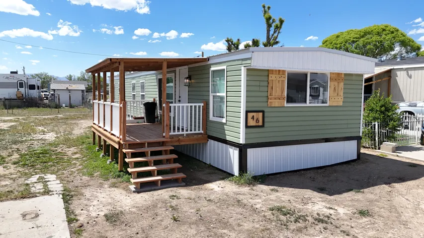 Green horizontal siding with white trim and a covered wooden deck featuring white railings