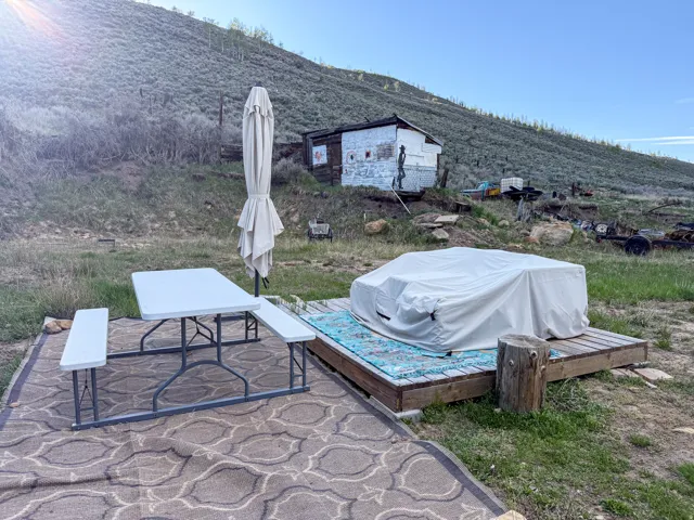 Outdoor entertaining area featuring a wooden deck, a patterned rug, and a picnic table