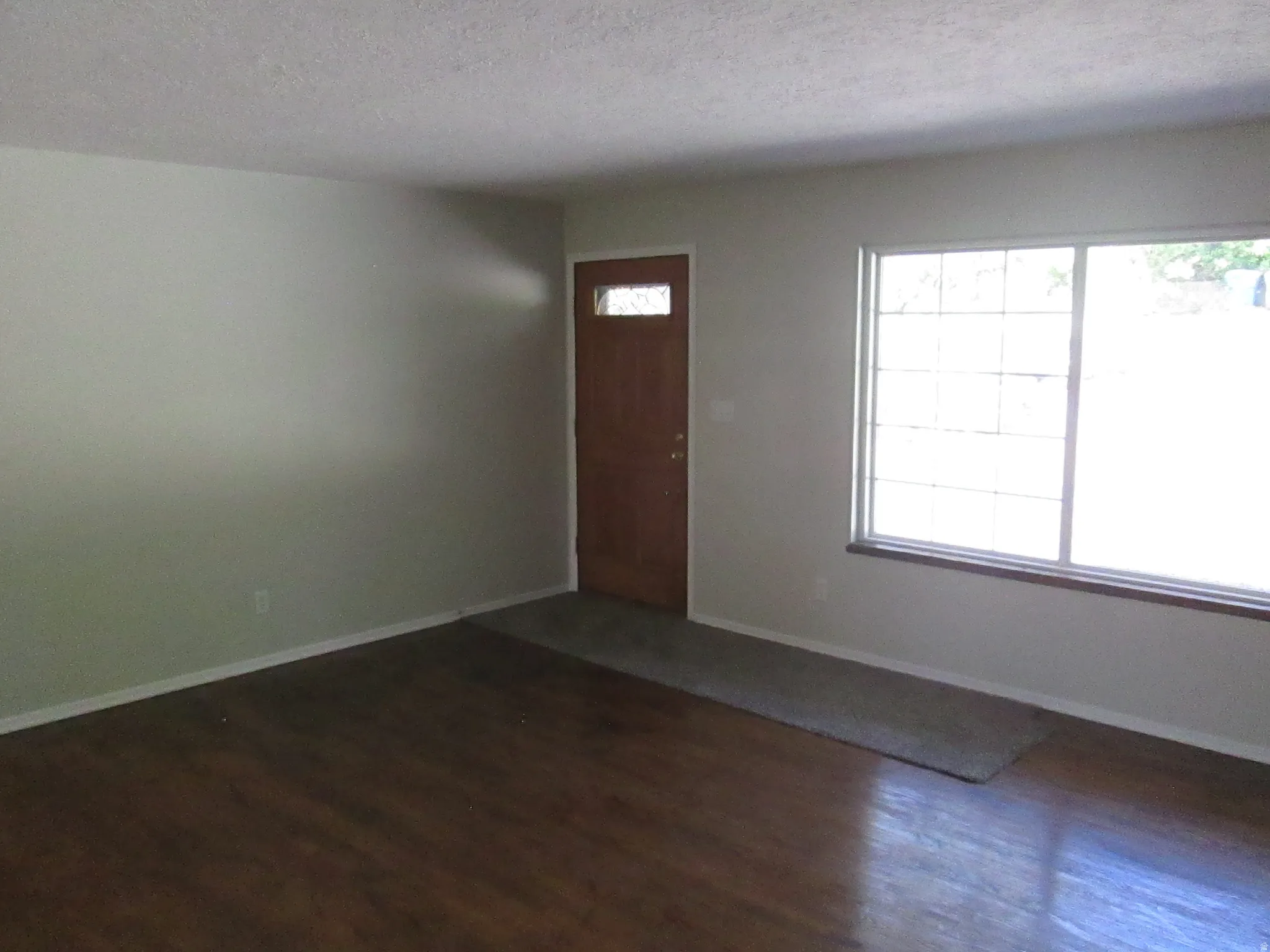 Spacious interior with wood-finish flooring, light-toned walls, and a large multi-pane window