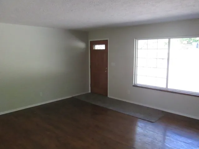 Spacious interior with wood-finish flooring, light-toned walls, and a large multi-pane window