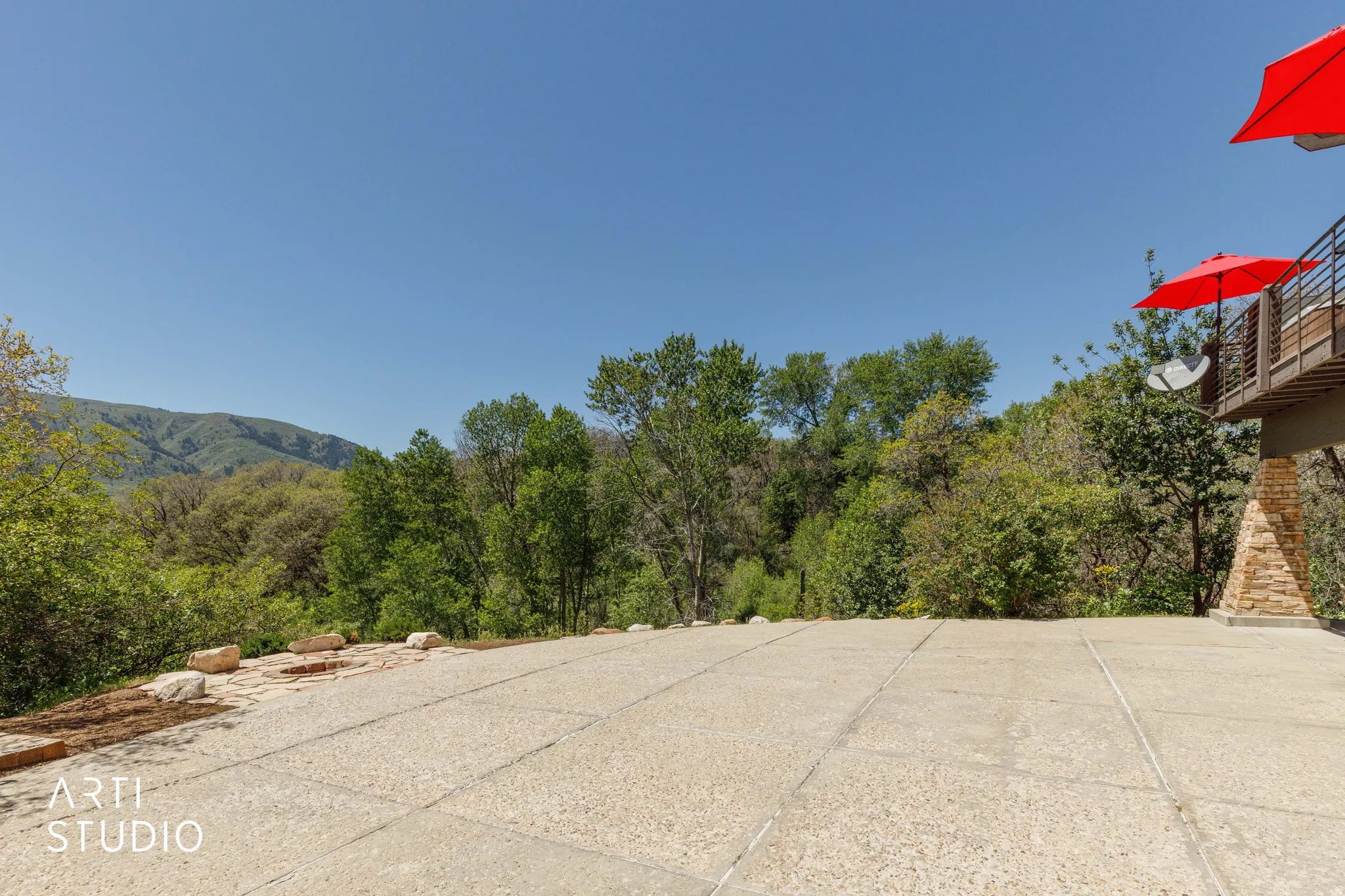 Expansive outdoor patio area featuring a concrete surface and natural stone edging
