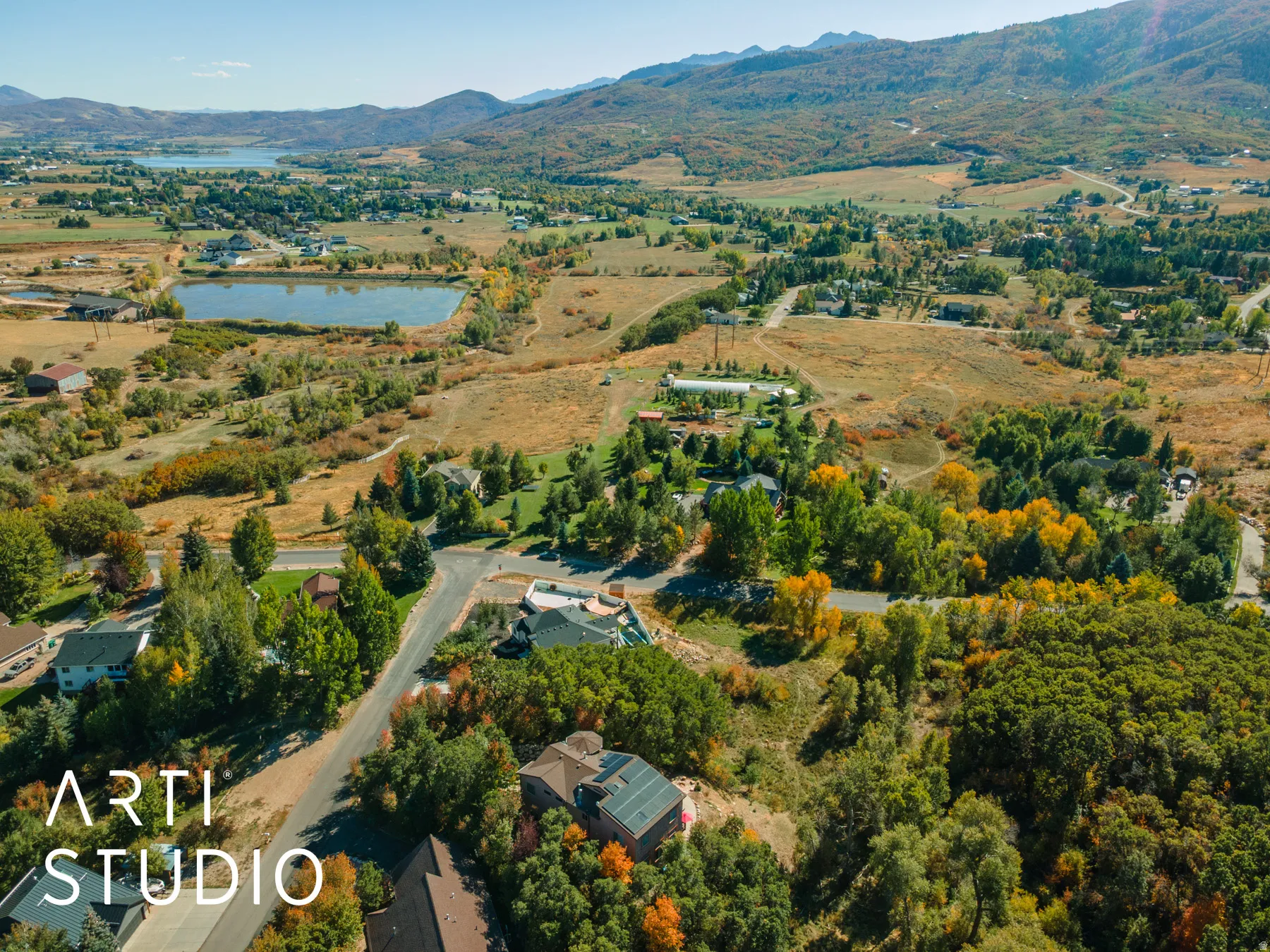 Expansive aerial landscape featuring a lake, surrounding natural terrain, and distant mountains