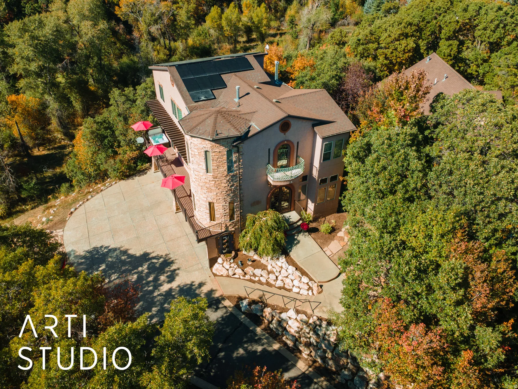 Mediterranean-style residence featuring a stone tower, solar panels, and a balcony with decorative railing