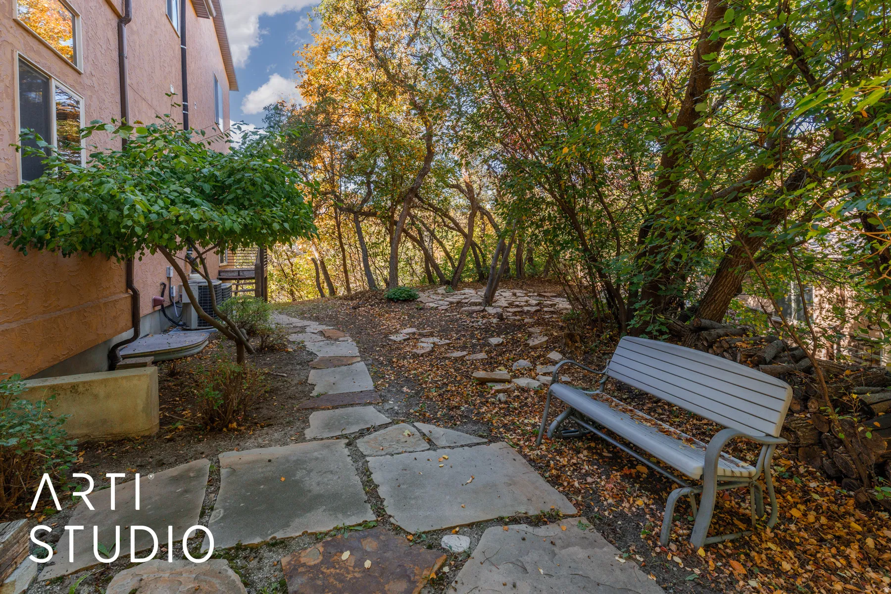 Stone paver pathway winding through mature trees and natural landscaping