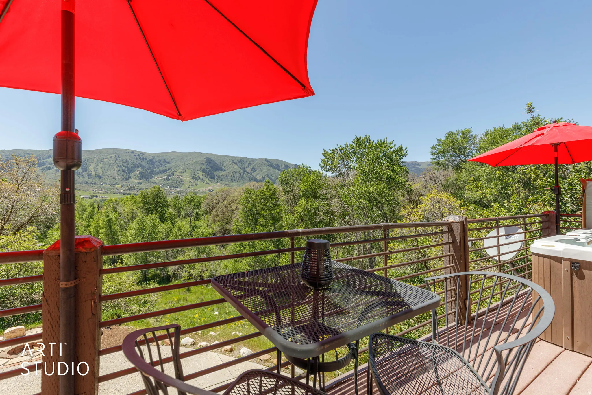 Outdoor deck featuring a hot tub, metal railing, and expansive mountain scenery