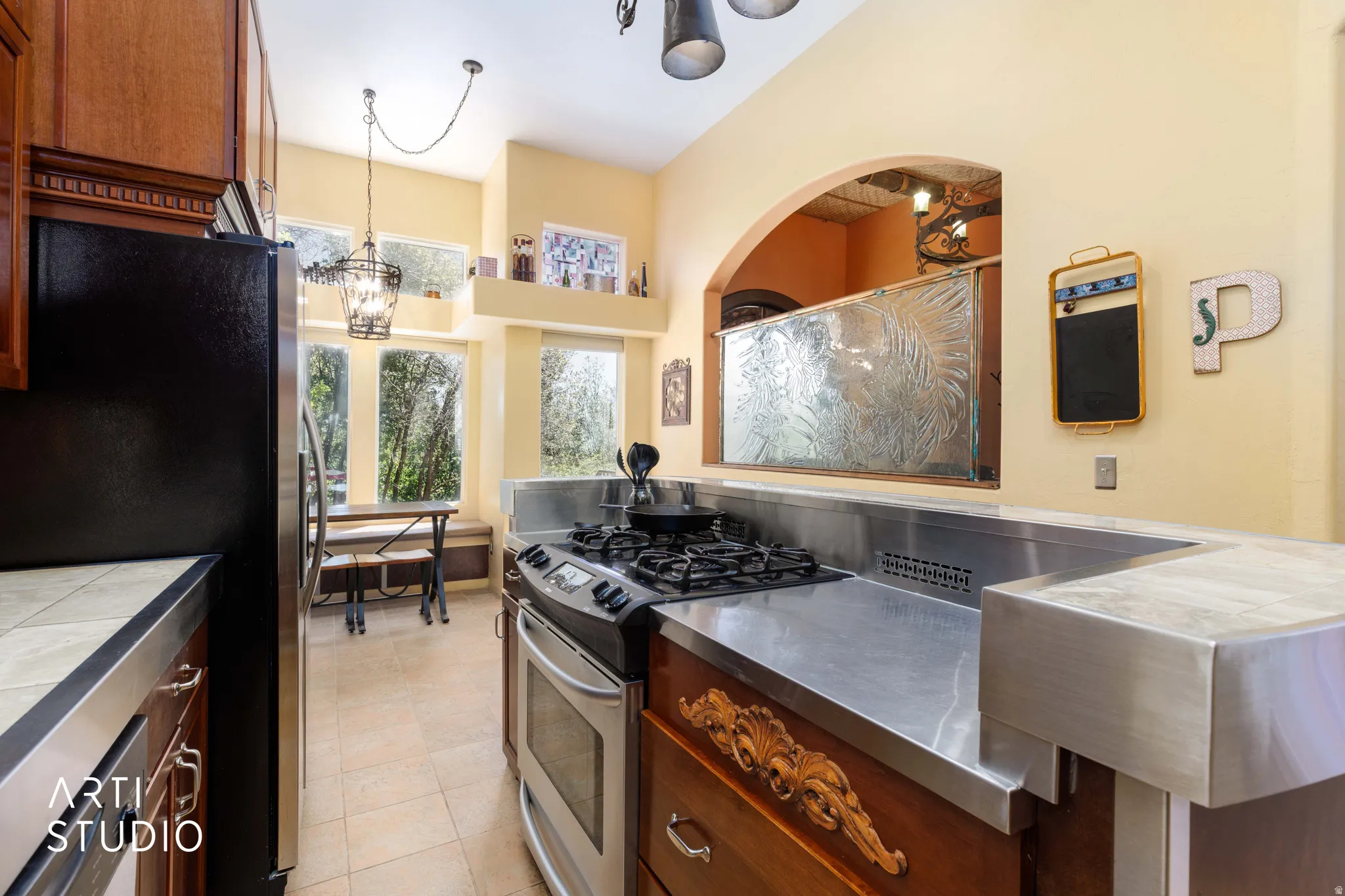 Kitchen featuring stainless steel countertops, a built-in gas range, warm wood cabinetry, and a black refrigerator