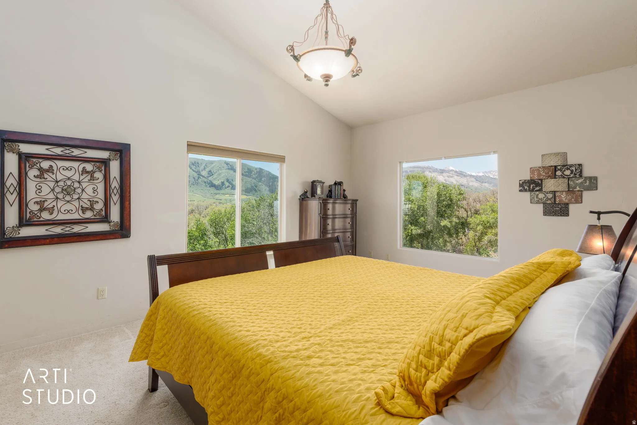 Vaulted ceiling bedroom featuring carpet flooring and a central chandelier