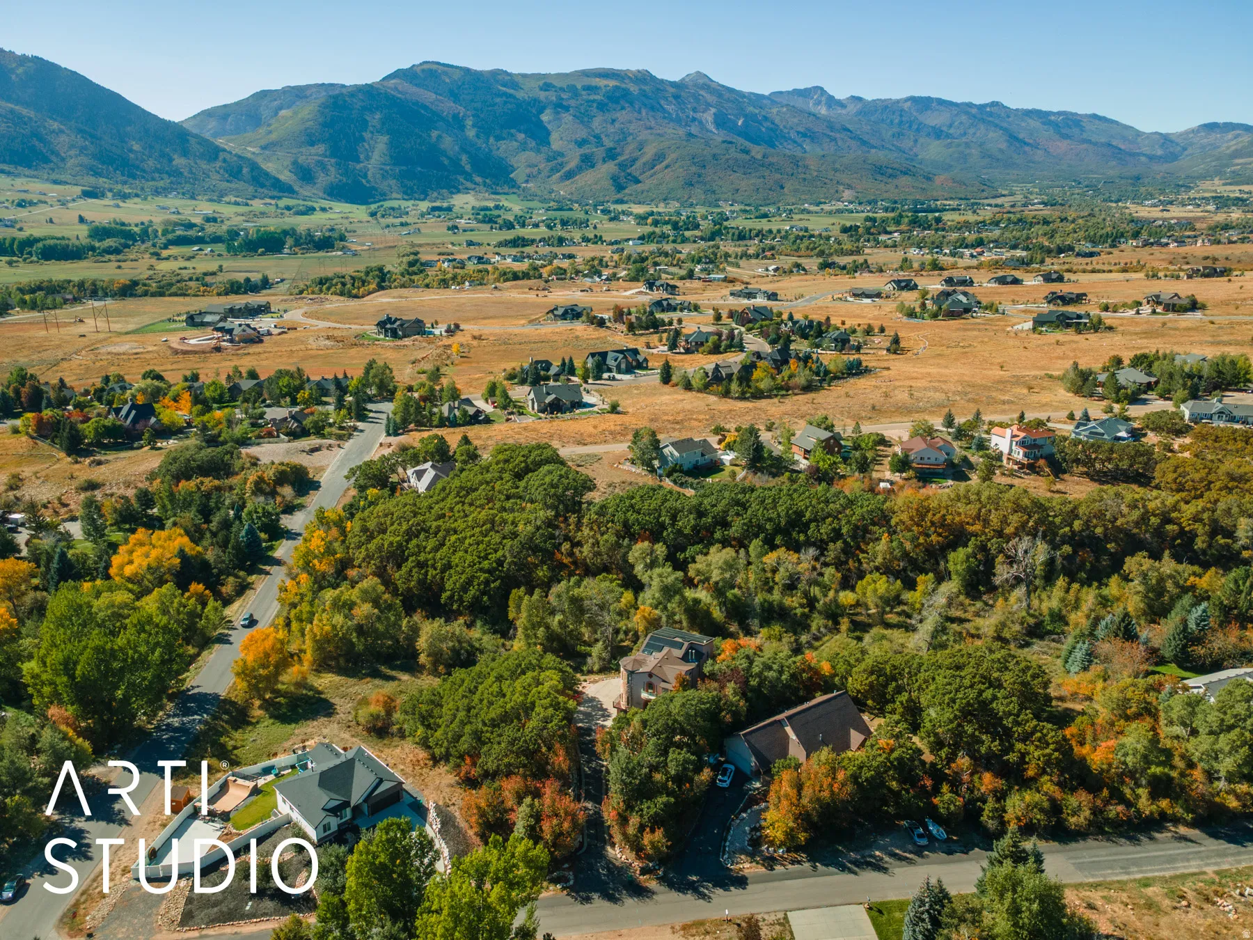 Expansive mountainous landscape featuring a residential area with mature trees and paved roads