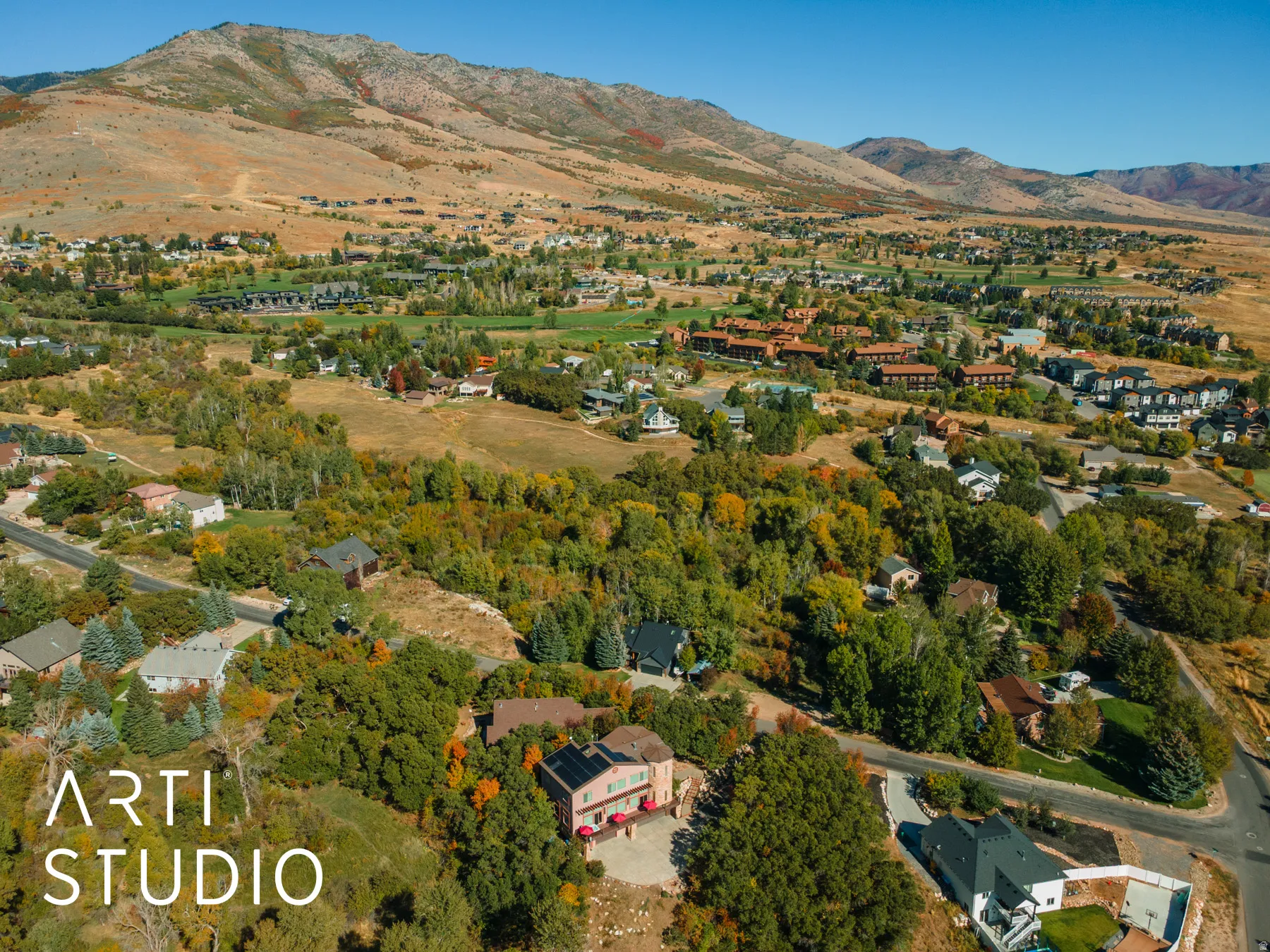 Aerial perspective showcasing a residential area nestled among varied topography with distant mountain ranges
