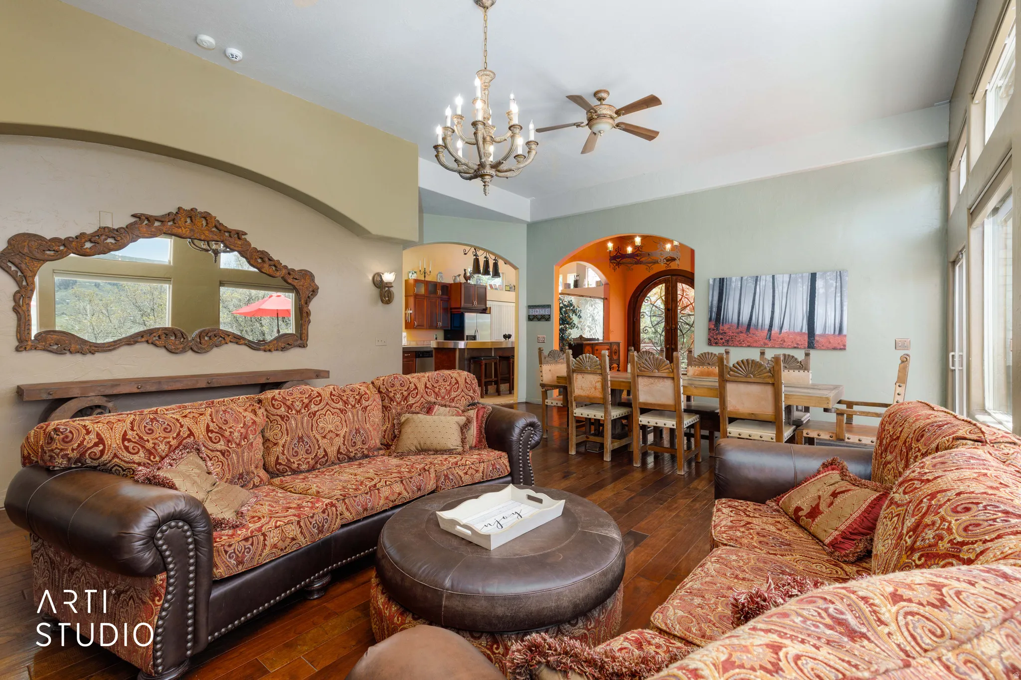 Spacious living area featuring wood-finish flooring, high ceilings, arched doorways, and abundant natural light from multiple windows